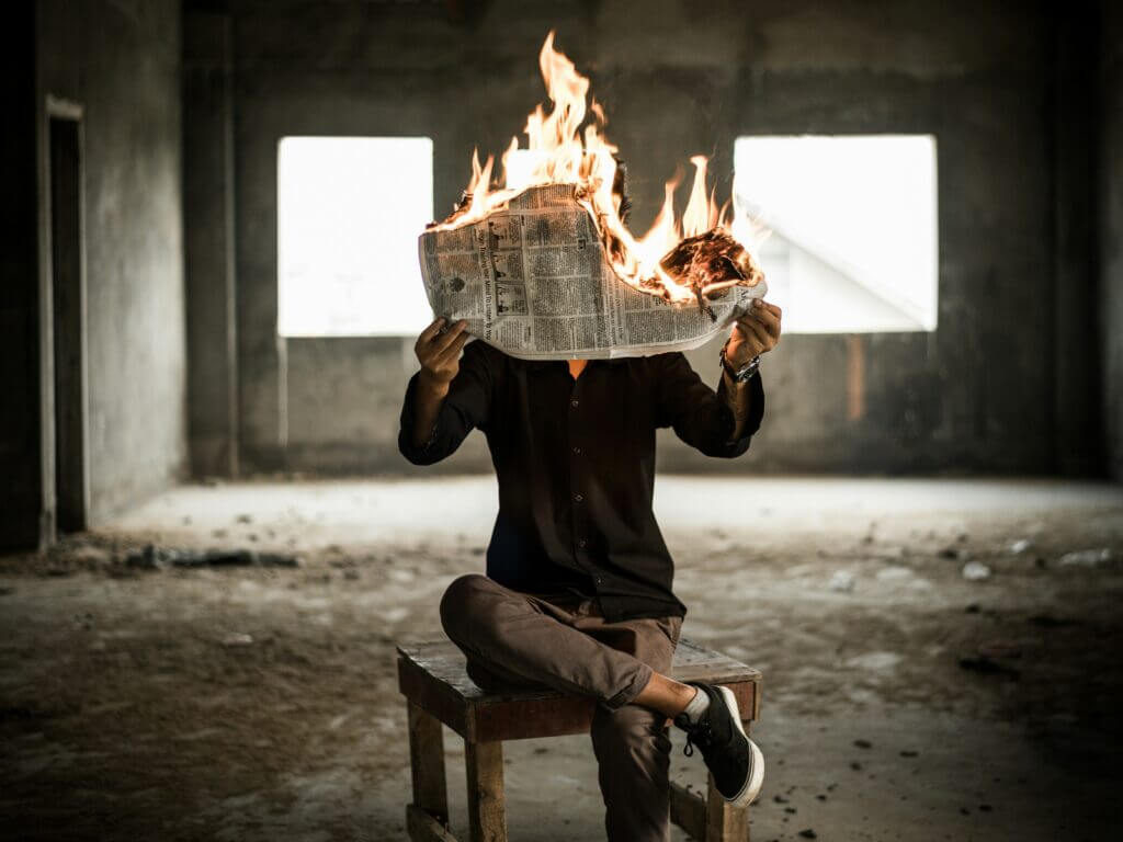 Un homme tient un journal en feu devant ses yeux