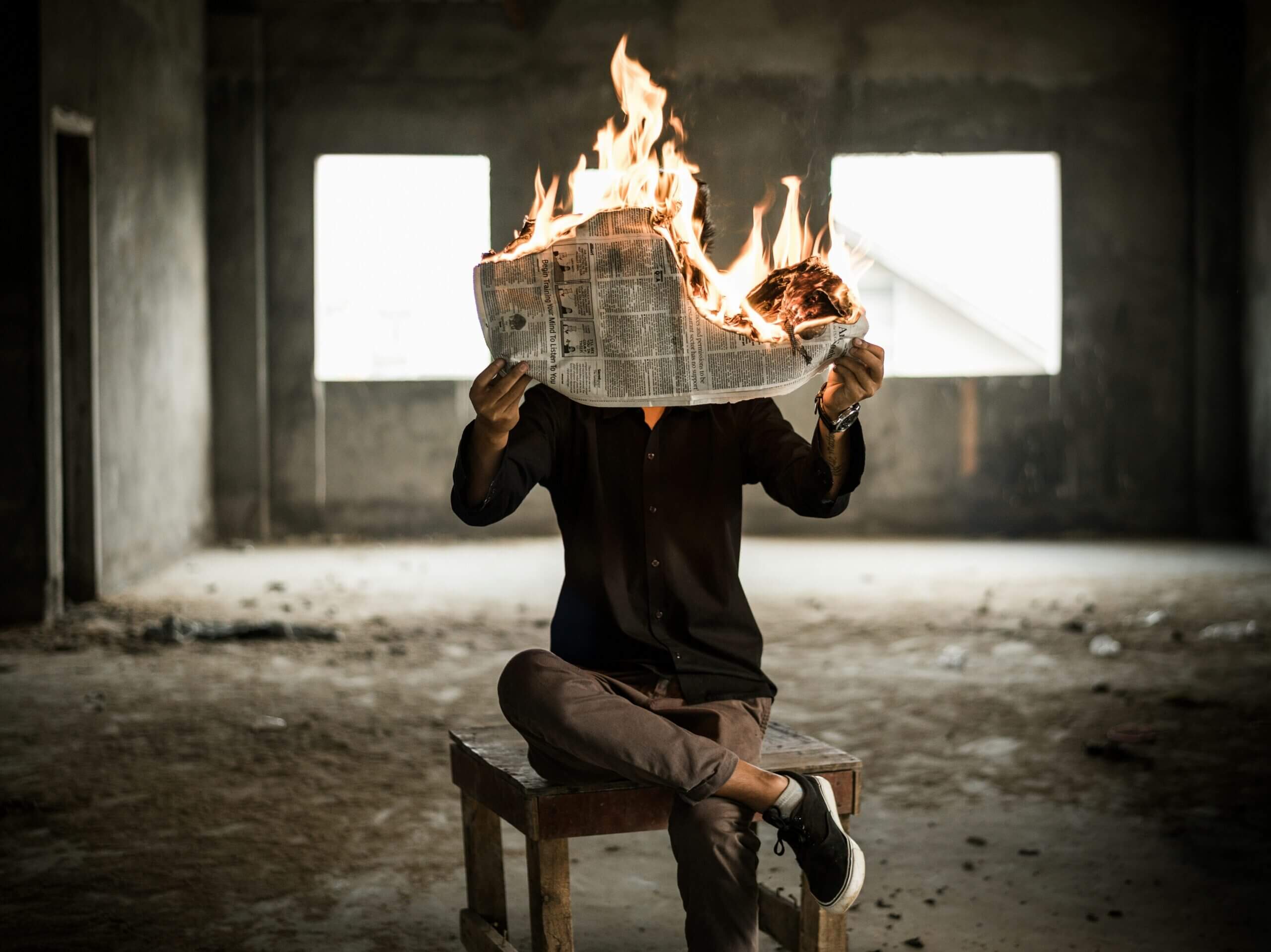 Un homme tient un journal en feu devant ses yeux