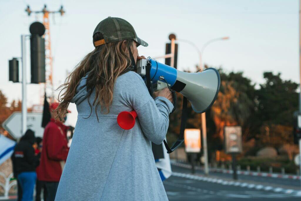 Une femme de dos parle dans un mégaphone